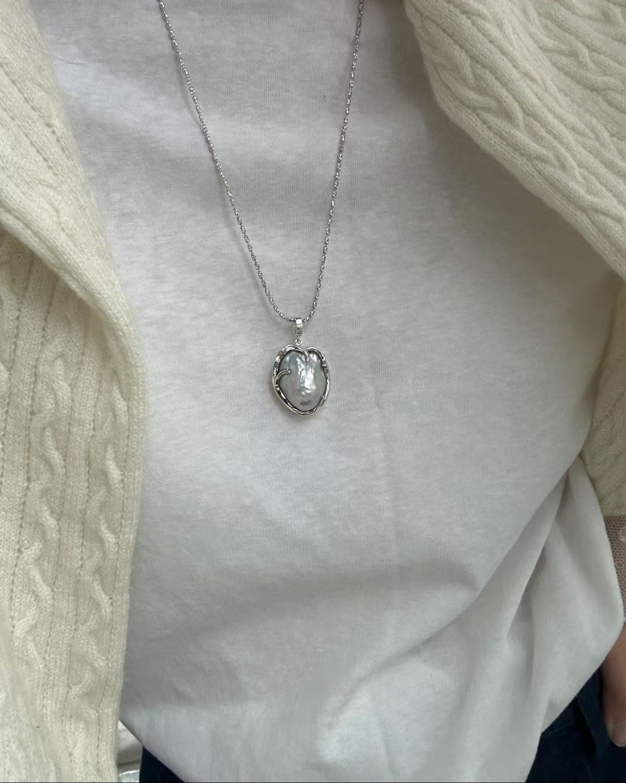 Silver necklace with a pendant on a plain background