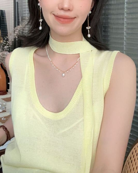 Woman wearing a light green sleeveless top with a blurred background