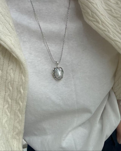 Silver necklace with a pendant on a plain background