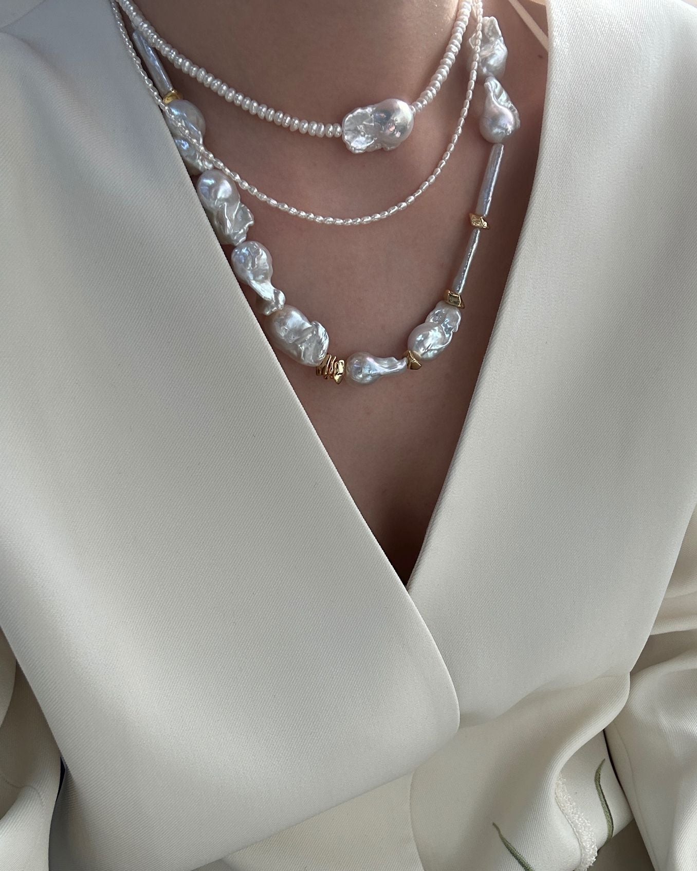Close-up of a pearl necklace worn with a white outfit