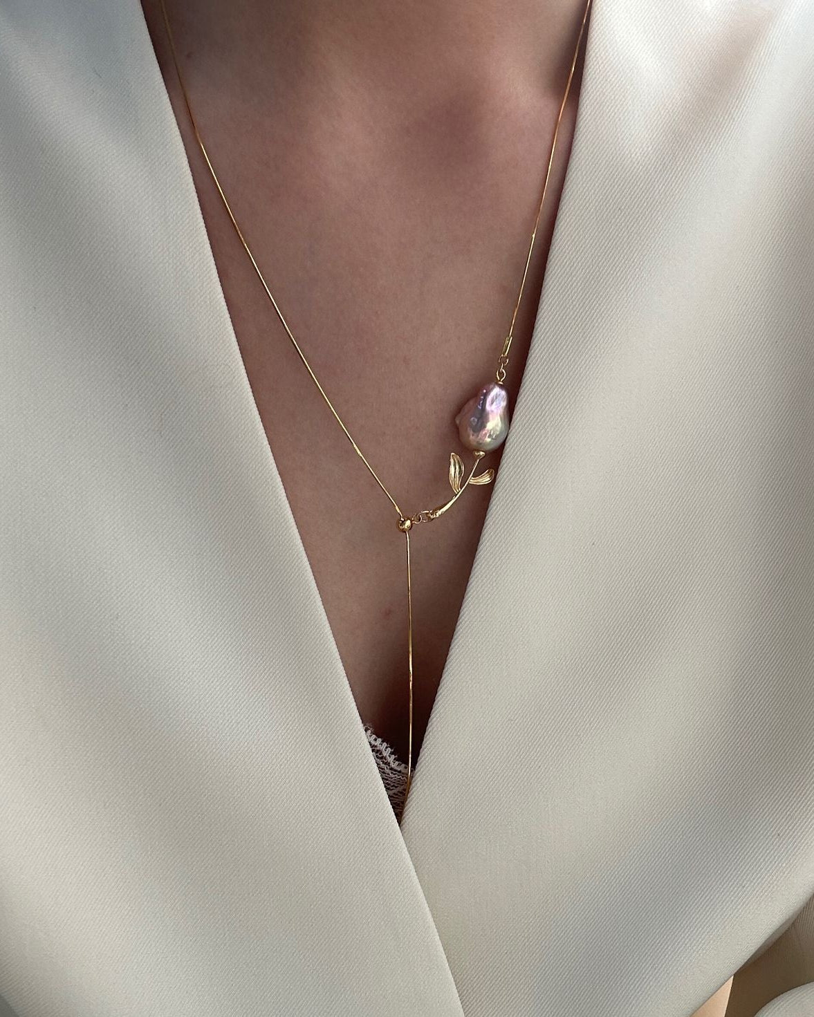 Necklace with a pink pendant on a white garment