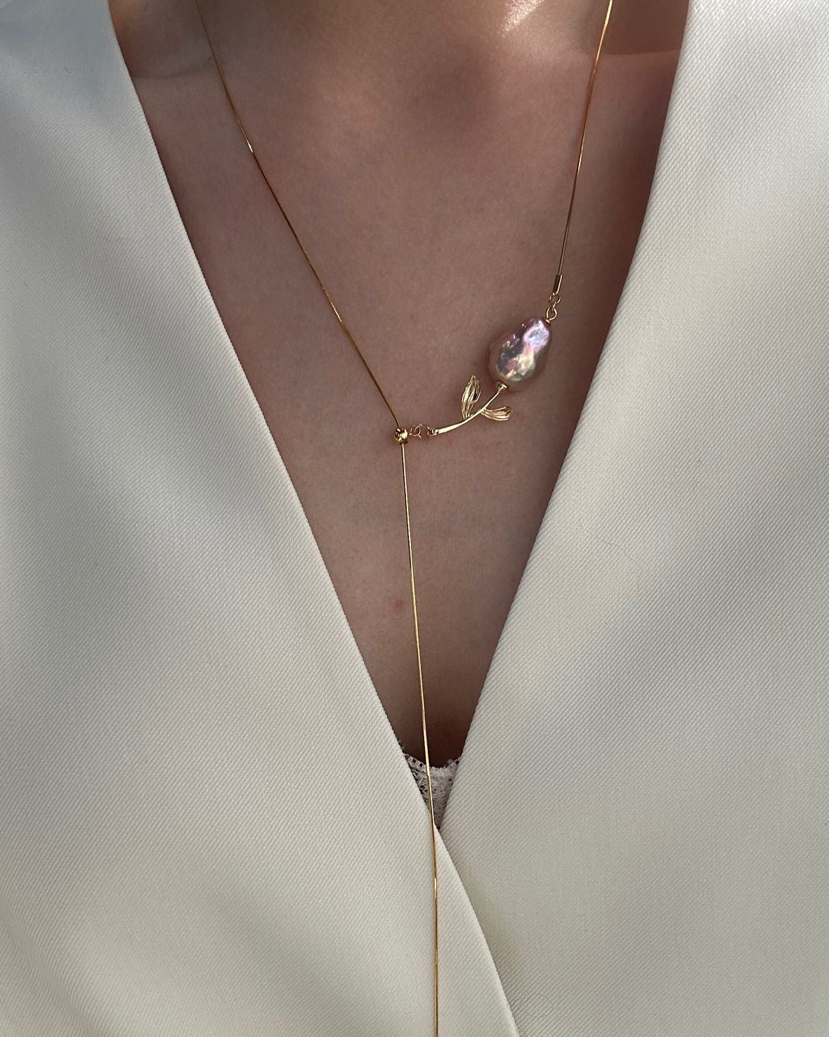 Necklace with a pink pendant on a white garment