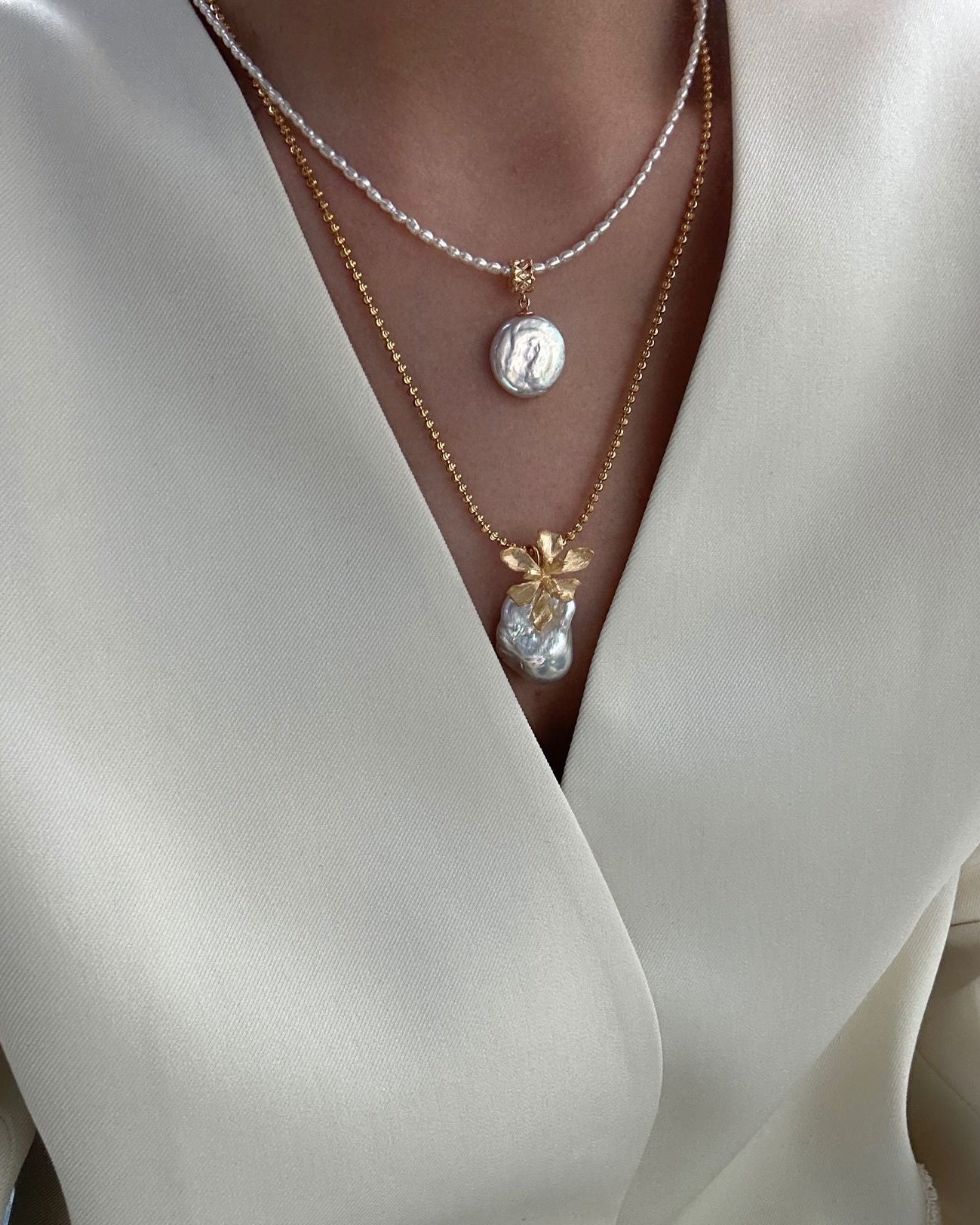 Close-up of a person wearing a pearl necklace with a white outfit