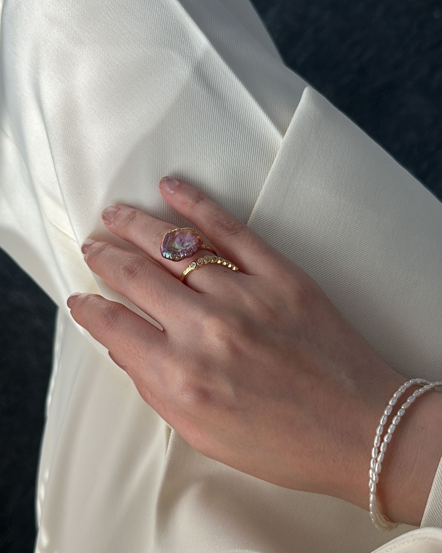 Hand wearing a ring on a white sleeve with a blurred background