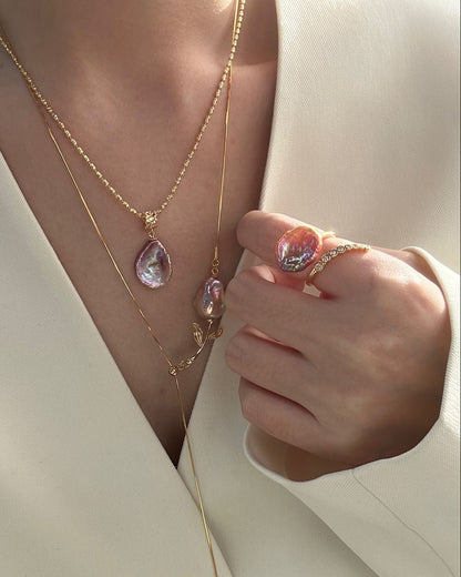 Close-up of a person wearing gold jewelry including a necklace, earrings, and ring.