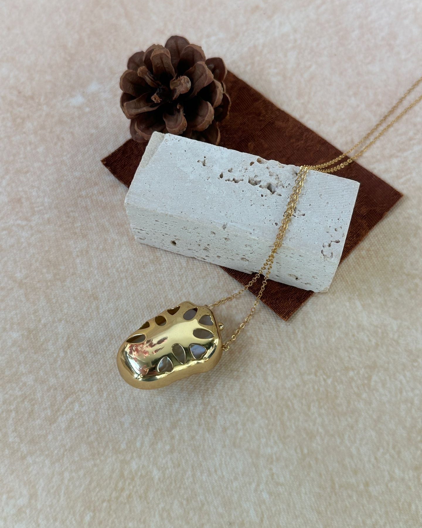 Gold necklace with a unique pendant on a textured surface