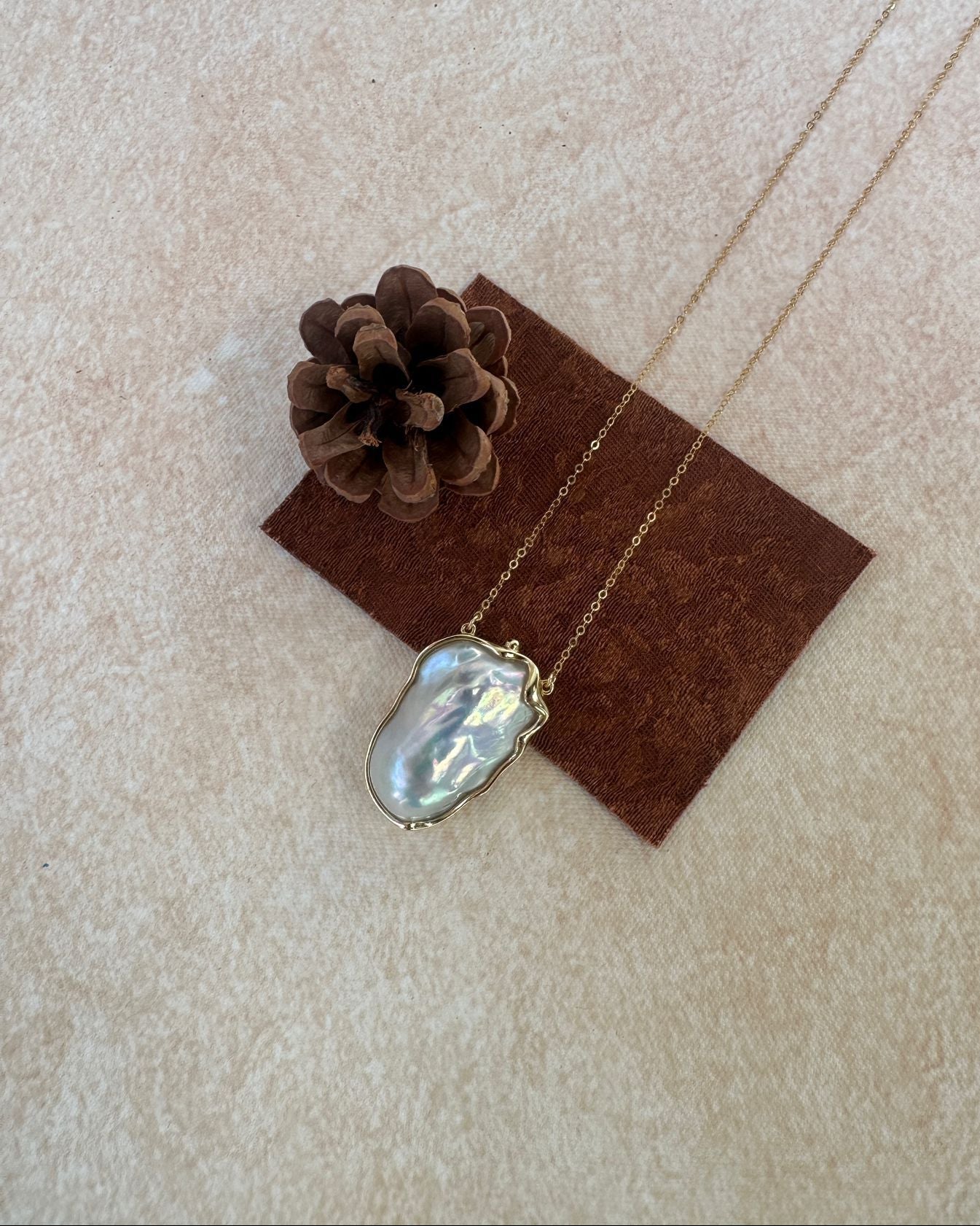 Necklace with a pendant on a brown card with a pine cone on a beige background