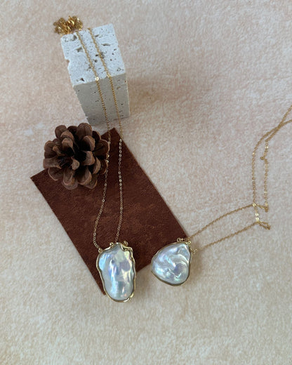 Pearl necklace on a brown card with a pine cone on a beige background