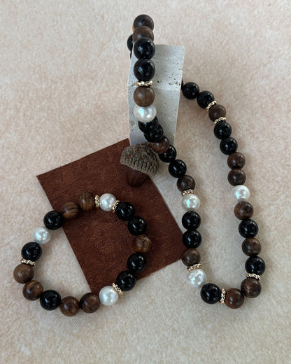 Beaded bracelet with brown, black, and white beads on a beige background
