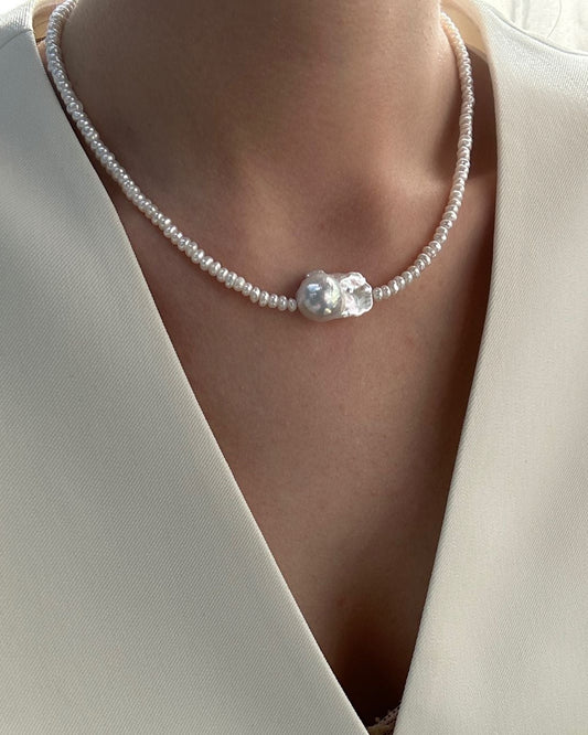 Pearl necklace worn by a person in a white outfit