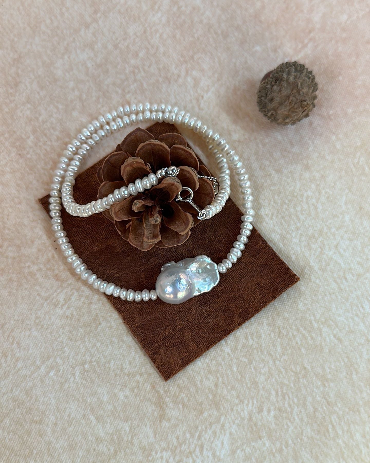 Pearl bracelet on a brown card with decorative elements on a beige background