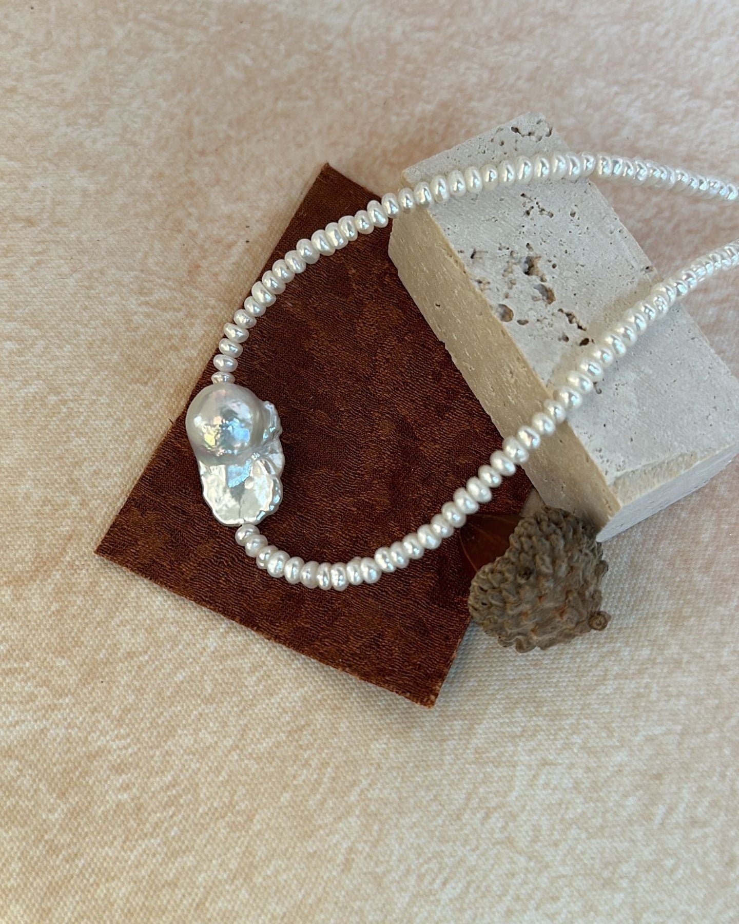 Pearl necklace with a large crystal pendant on a textured surface