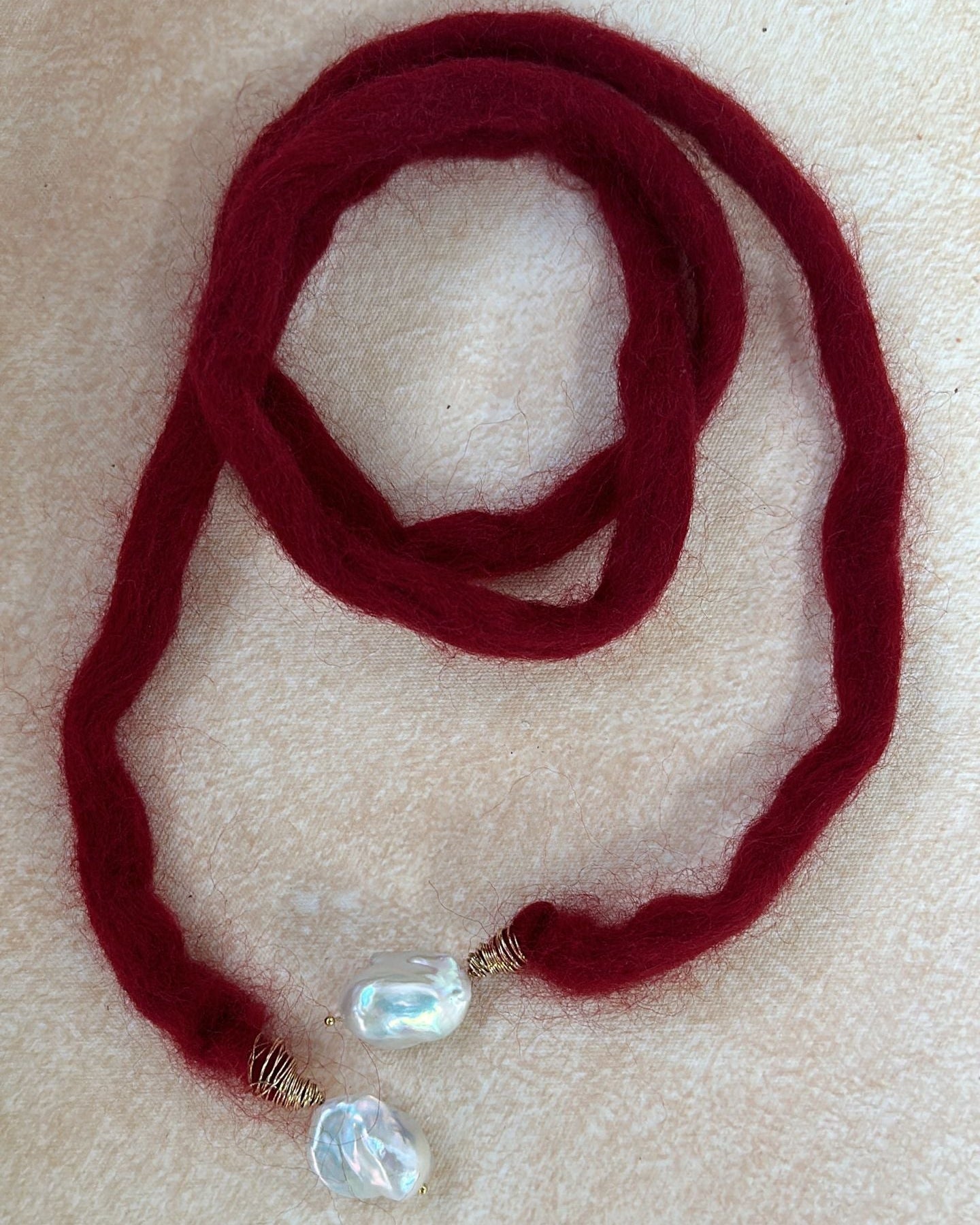 Red yarn necklace with crystal pendants on a beige surface