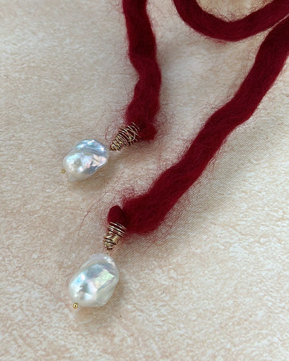 Red yarn with pearl beads on a beige surface