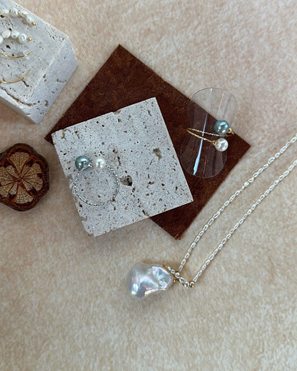 Silver jewelry including a necklace and earrings on a textured surface