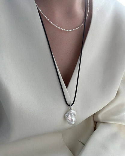 Necklace with a clear pendant on a white outfit