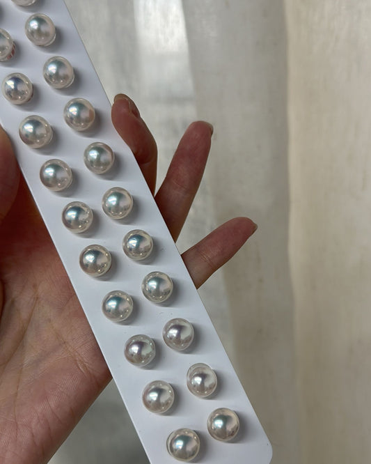 Set of pearl earrings on a white card held by a hand against a neutral background