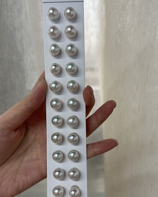 Pack of silver earrings held by a hand against a neutral background